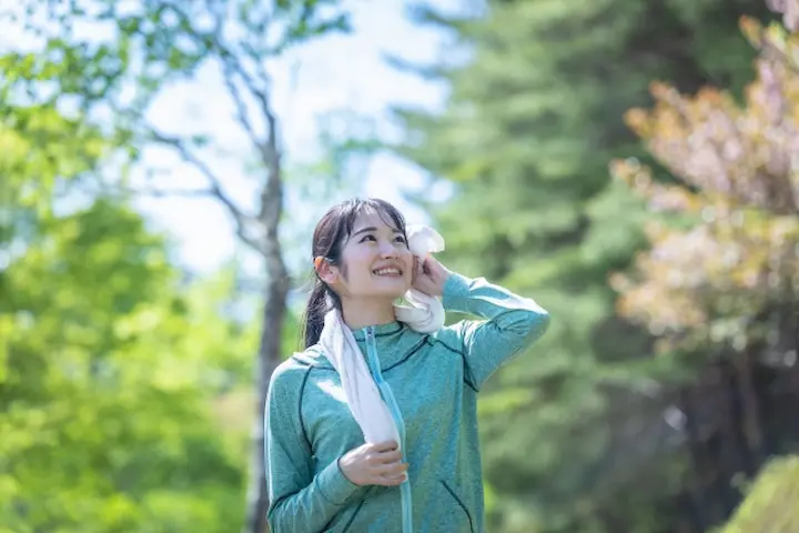 よもぎ蒸しで夏の疲れをリセットし、秋の公園で晴れやかな表情を浮かべる健康的な女性