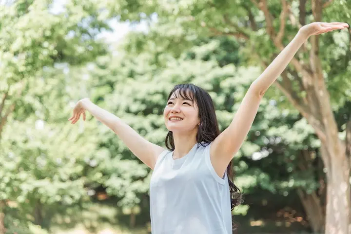 野原で深呼吸をする、活力を取り戻した女性